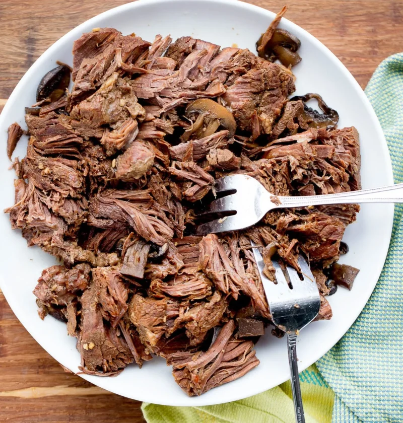 pioneer woman 1 pot roast 3 easy meals: shredded beef on a plate with mushrooms and pot juices