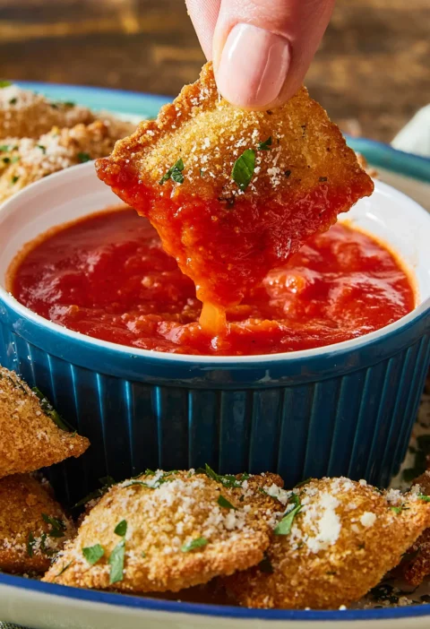 pioneer woman air fryer ravioli golden and crispy on a plate with parmesan and marinara sauce