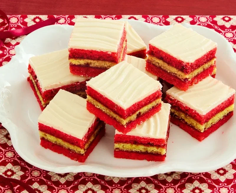pioneer woman almond layer cookies with red and white layers, raspberry jam filling and white chocolate topping on a plate