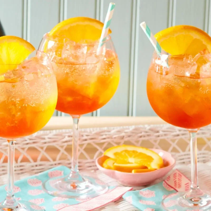 Pioneer Woman Aperol Spritz cocktail in a wine glass filled with ice, showing the bright orange drink topped with an orange slice