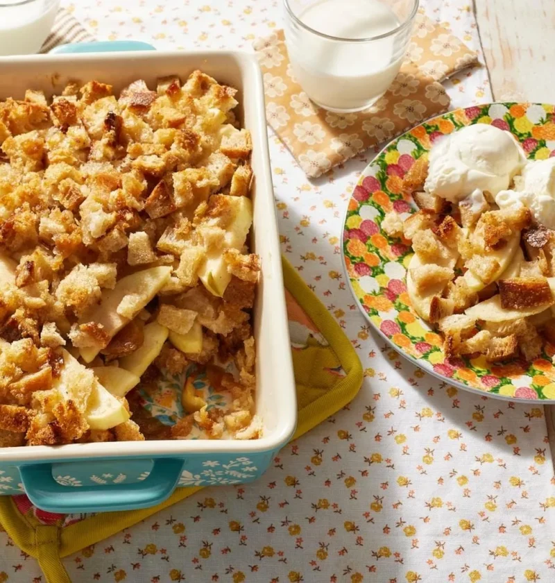 Golden-topped apple betty with layers of diced wheat bread, sliced Granny Smith apples, and brown sugar in a baking dish