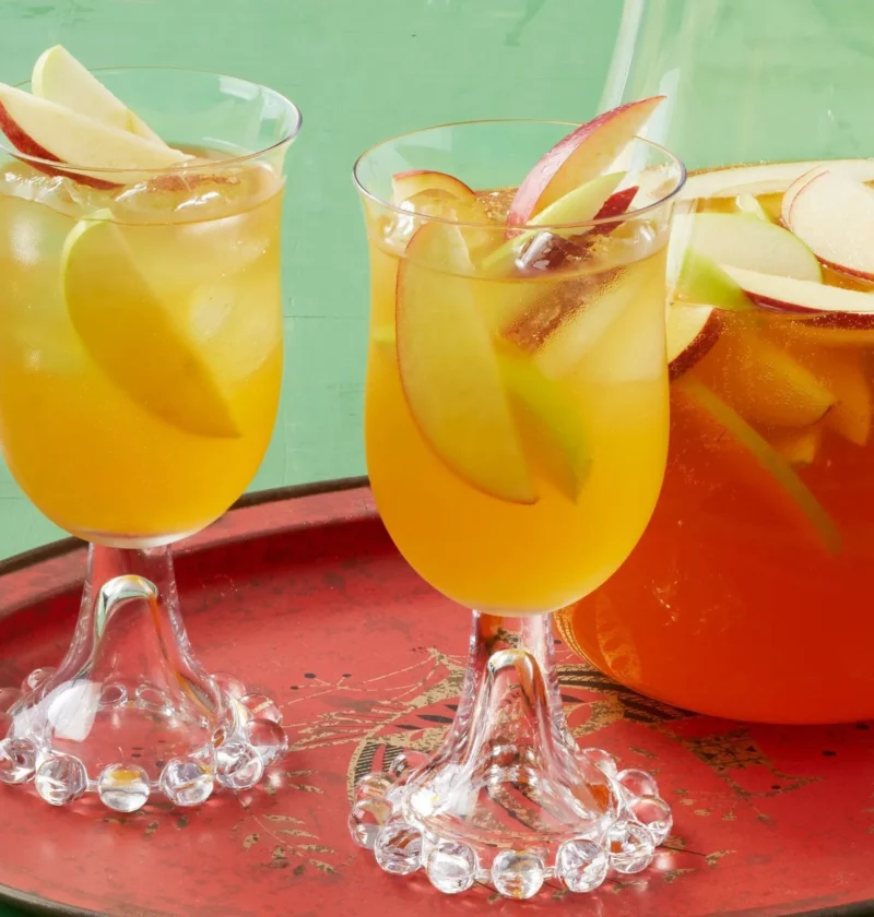 Pioneer woman apple cider sangria in a glass pitcher with thin apple slices floating in a golden cider and white wine mixture