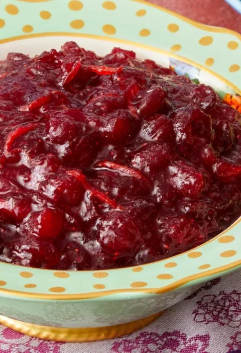 A bowl of chunky apple cranberry sauce with visible cranberries and diced apple pieces in a glossy, ruby-red sauce