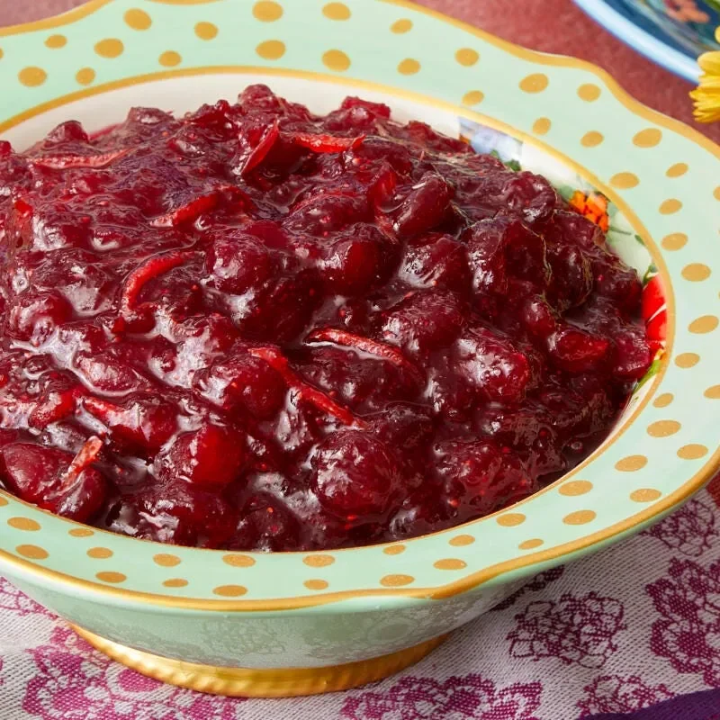 A bowl of chunky apple cranberry sauce with visible cranberries and diced apple pieces in a glossy, ruby-red sauce