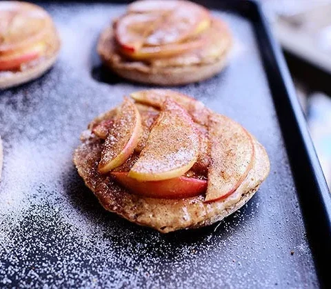 Apple peanut butter delights on a cookie sheet with caramelized cinnamon sugar topping on English muffin halves