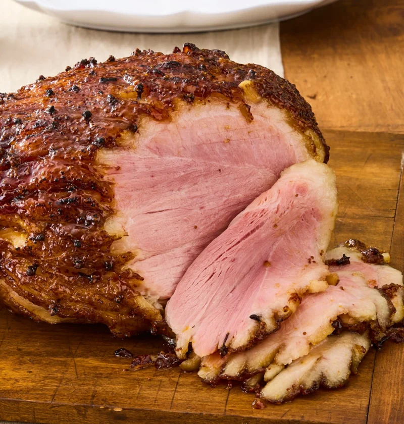 Sliced apricot and mustard glazed ham with a shiny caramelized glaze on a serving platter