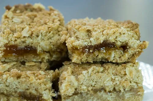 Pioneer woman apricot bars stacked on a plate showing the crumbly oat topping and apricot preserves layer