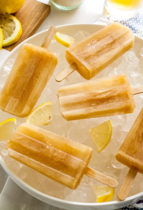 Pioneer Woman Arnold Palmer popsicles lined up on a surface with lemon slices nearby
