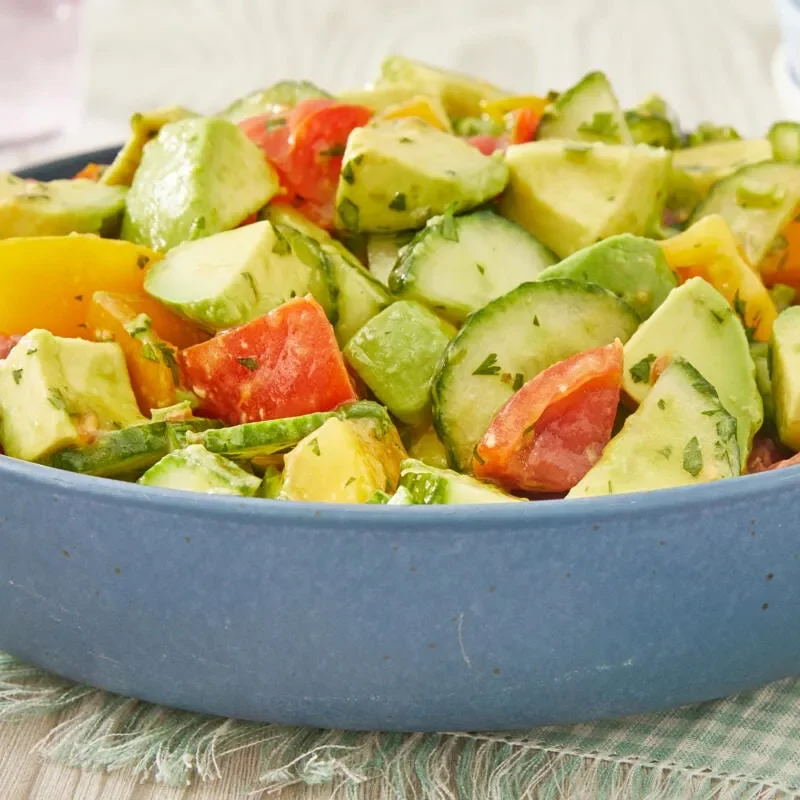 Bowl of pioneer woman avocado salad with diced avocados, tomatoes, cucumber and green onions topped with fresh cilantro