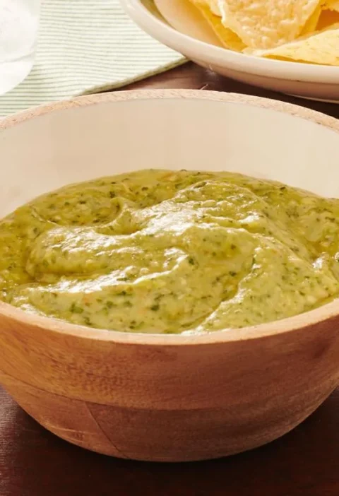 Bowl of creamy green pioneer woman avocado salsa verde served with tortilla chips for dipping
