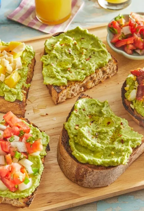 Avocado toast topped with grated hard-boiled egg, crumbled bacon, and red pepper flakes on broiled sourdough bread