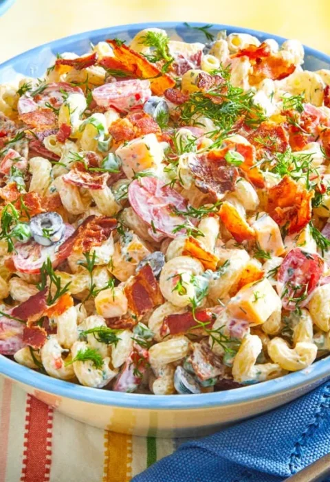Pioneer Woman bacon ranch pasta salad topped with crumbled bacon and fresh dill in a large serving bowl