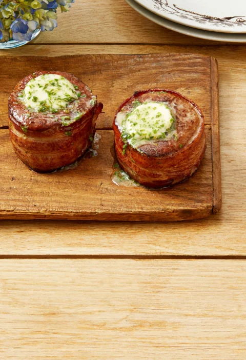 Bacon wrapped filet steaks topped with melting cowboy butter on a plate