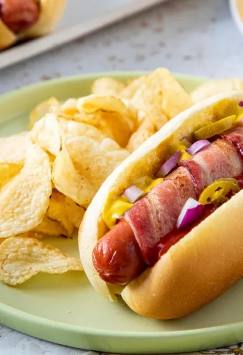 Bacon-wrapped hot dogs lined up on a wire rack with crispy golden bacon spirals, ready for a pioneer woman bacon wrapped hot dogs dinner