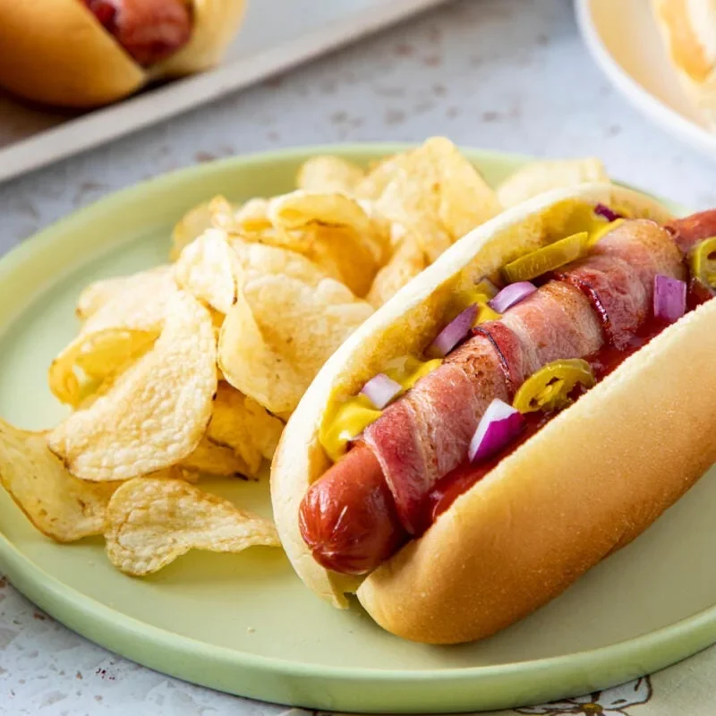 Bacon-wrapped hot dogs lined up on a wire rack with crispy golden bacon spirals, ready for a pioneer woman bacon wrapped hot dogs dinner