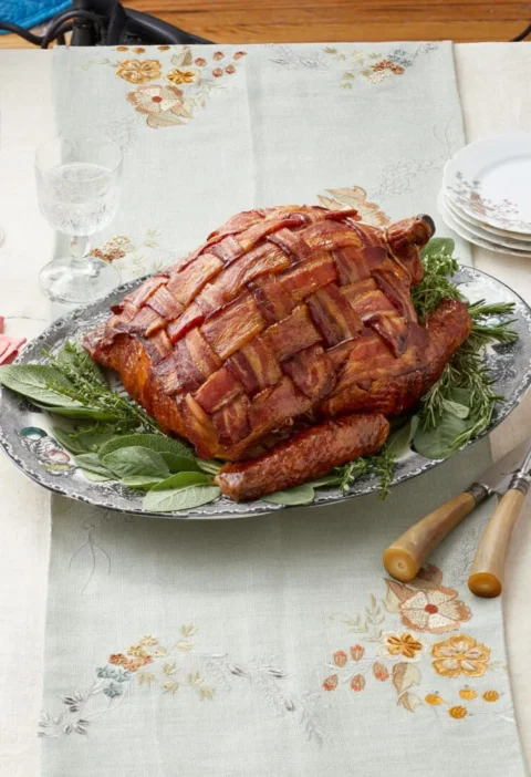 Bacon wrapped turkey with a woven bacon lattice on a roasting rack, golden and crispy from the oven