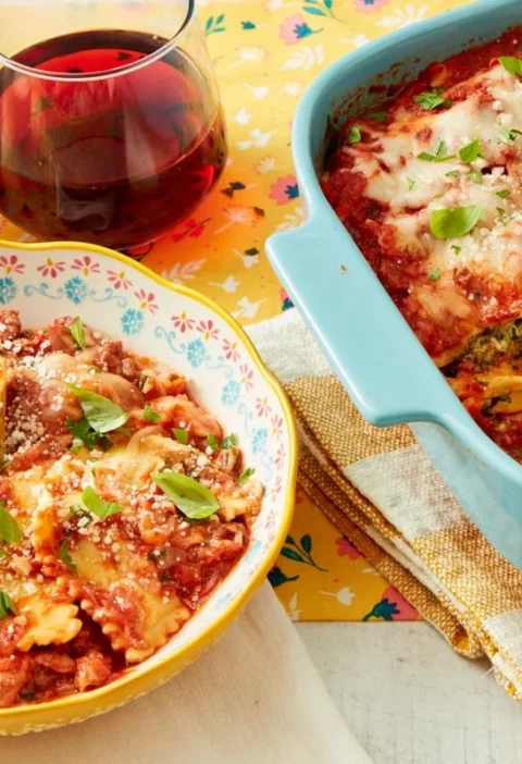 Baked ravioli casserole in a dish topped with melted mozzarella cheese, fresh basil and parsley