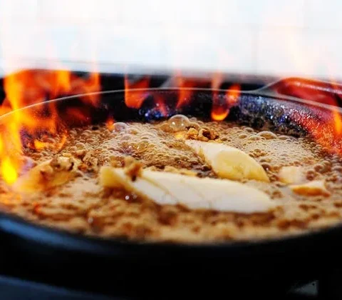 Pioneer Woman bananas foster served over vanilla ice cream with caramelized bananas and walnuts in a rich butter rum sauce