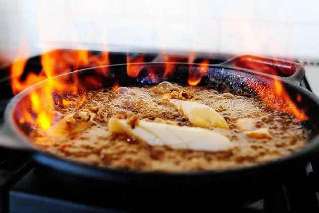 Pioneer Woman bananas foster served over vanilla ice cream with caramelized bananas and walnuts in a rich butter rum sauce
