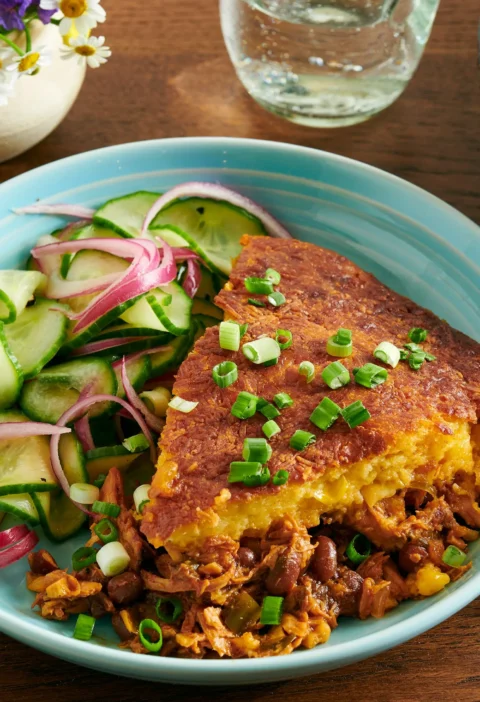 Cast iron skillet filled with pioneer woman BBQ chicken cornbread bake showing golden cornbread topping with melted cheddar and green onions