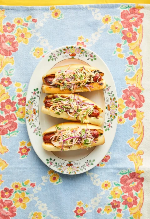 Pioneer Woman BBQ hot dogs with cilantro slaw in brioche buns topped with a colorful cabbage slaw on a serving platter
